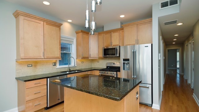 kitchen with light brown cabinetry, stainless steel appliances, a center island, and sink