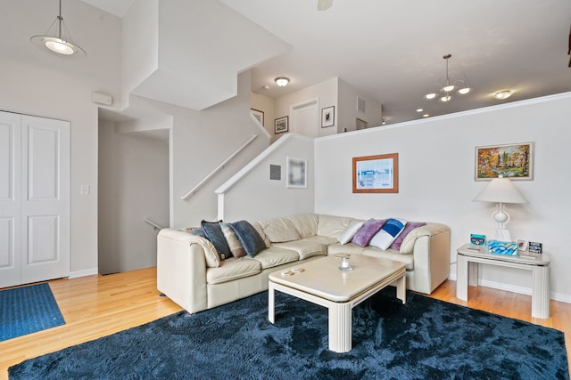 living room with hardwood / wood-style flooring, a towering ceiling, and an inviting chandelier