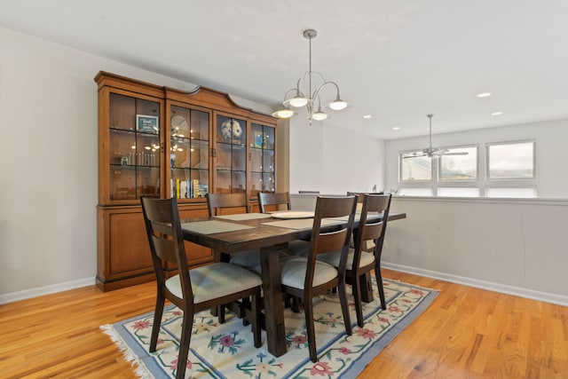 dining space featuring light hardwood / wood-style floors and ceiling fan with notable chandelier