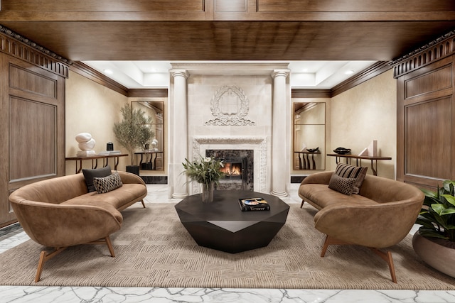 living room with ornamental molding, a high end fireplace, a tray ceiling, and decorative columns