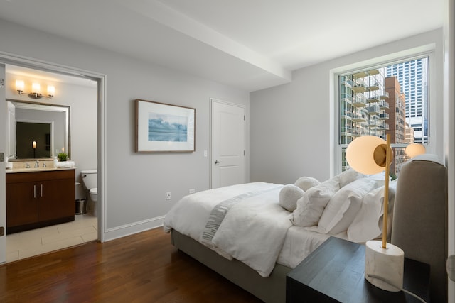 bedroom featuring ensuite bath, dark hardwood / wood-style floors, and sink