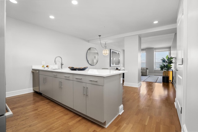 kitchen with light countertops, dishwasher, a peninsula, and a sink