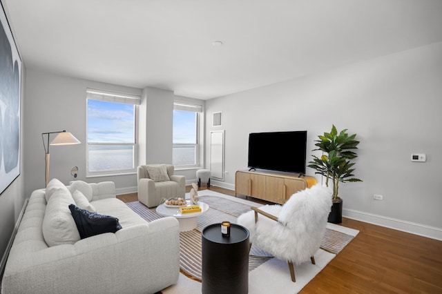 living room featuring visible vents, baseboards, and wood finished floors