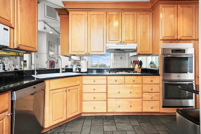 kitchen featuring dark stone countertops, appliances with stainless steel finishes, and sink