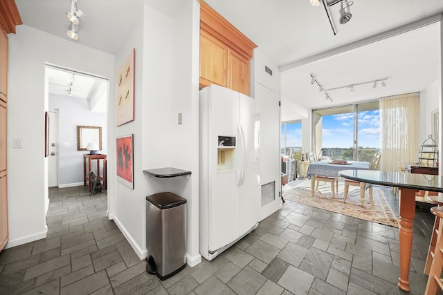 kitchen with white fridge with ice dispenser, light brown cabinets, and track lighting