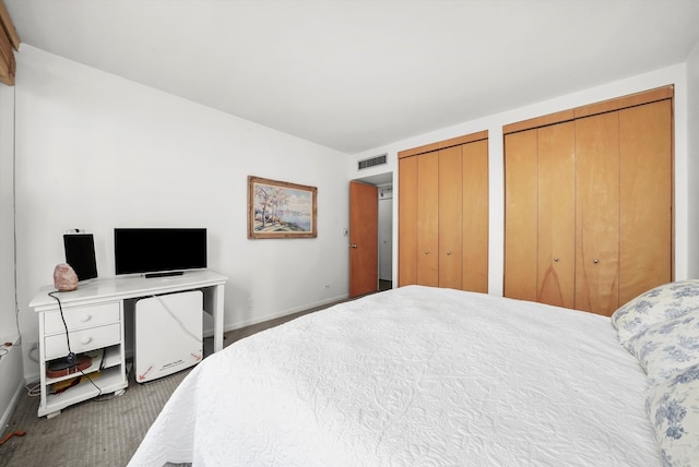 bedroom featuring dark carpet and multiple closets