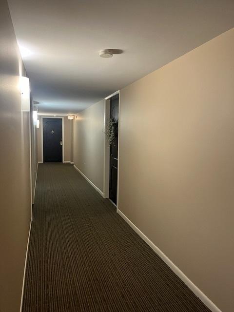 corridor featuring dark colored carpet