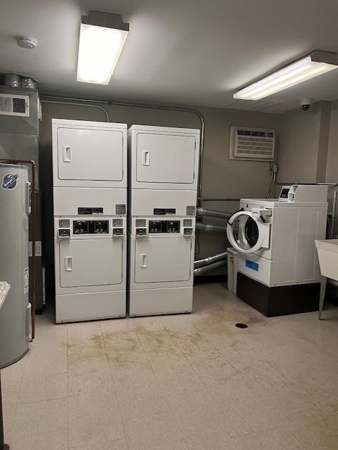 laundry room featuring separate washer and dryer, an AC wall unit, and stacked washer / drying machine