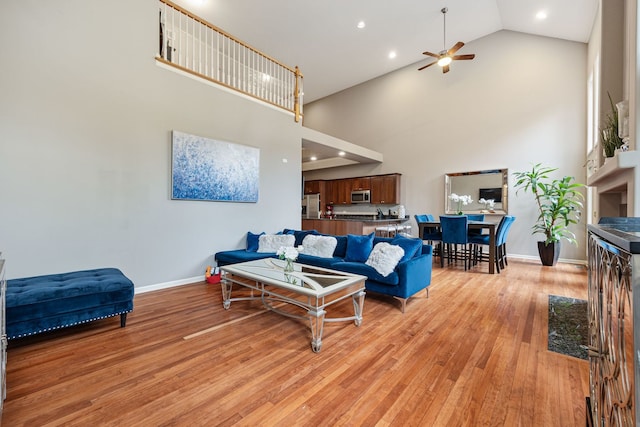 living room featuring high vaulted ceiling, light wood-type flooring, and ceiling fan