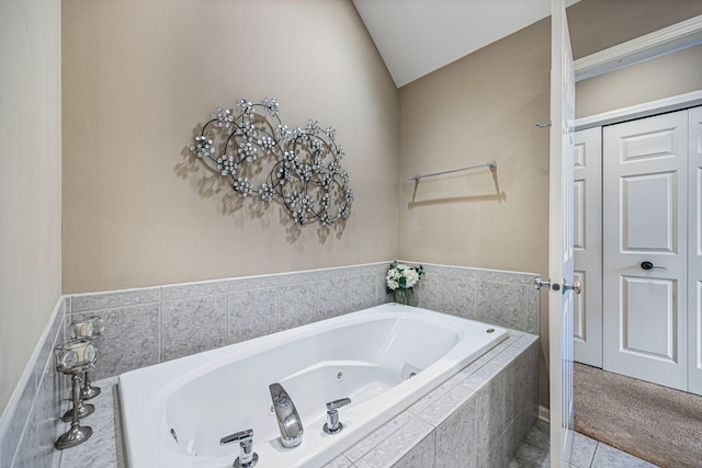 bathroom featuring lofted ceiling, tile patterned floors, and a relaxing tiled tub