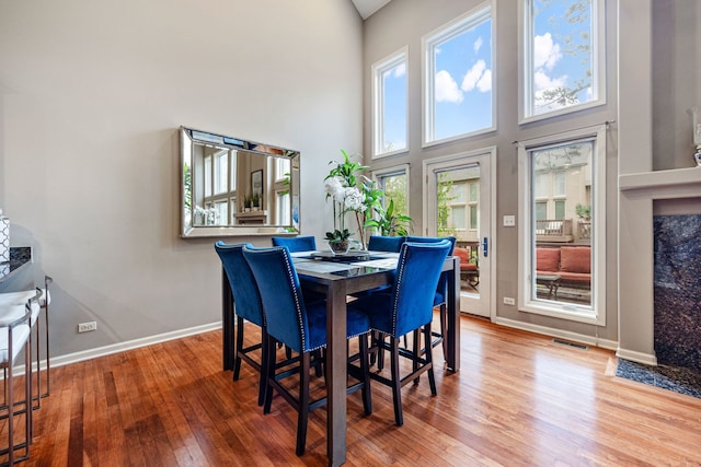 dining area featuring a towering ceiling and hardwood / wood-style floors