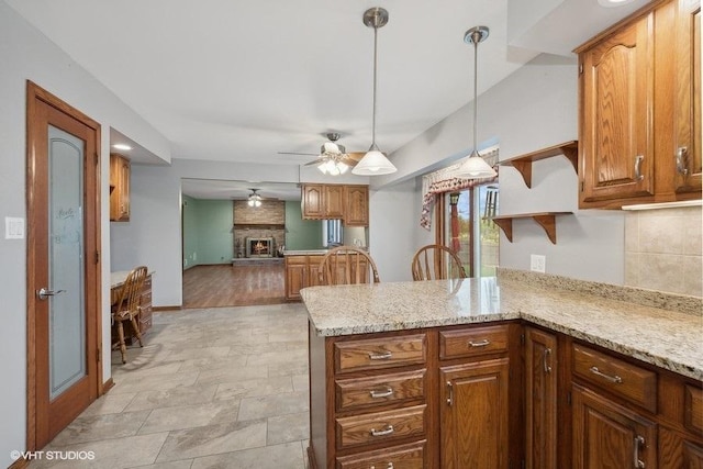 kitchen featuring ceiling fan, hanging light fixtures, stainless steel appliances, a kitchen breakfast bar, and light stone counters