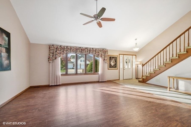 unfurnished living room with ceiling fan with notable chandelier, dark hardwood / wood-style flooring, and high vaulted ceiling