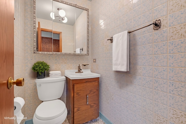 bathroom with tile walls, vanity, and toilet