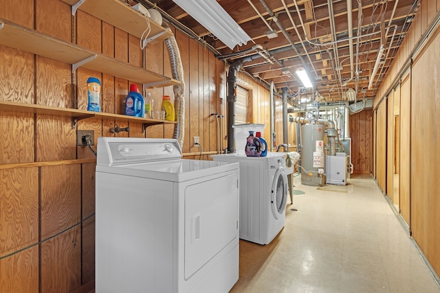 laundry area with washer and dryer, wooden walls, and gas water heater