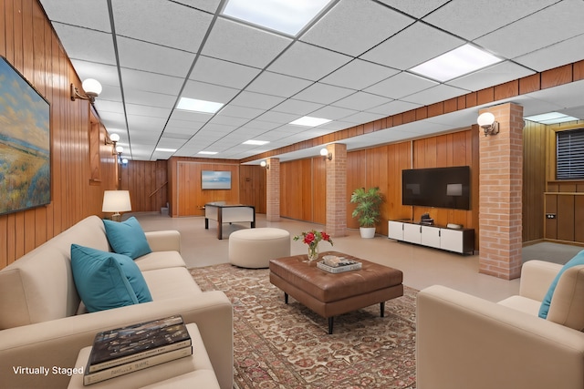 living room with decorative columns, a paneled ceiling, and wood walls