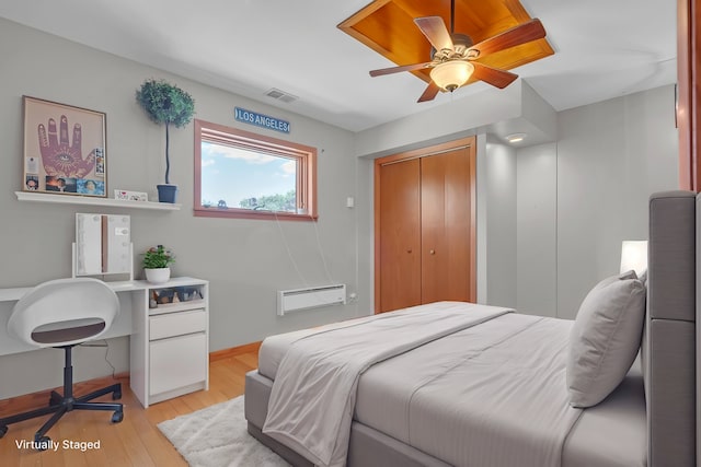 bedroom with a closet, a wall mounted AC, light wood-type flooring, and ceiling fan