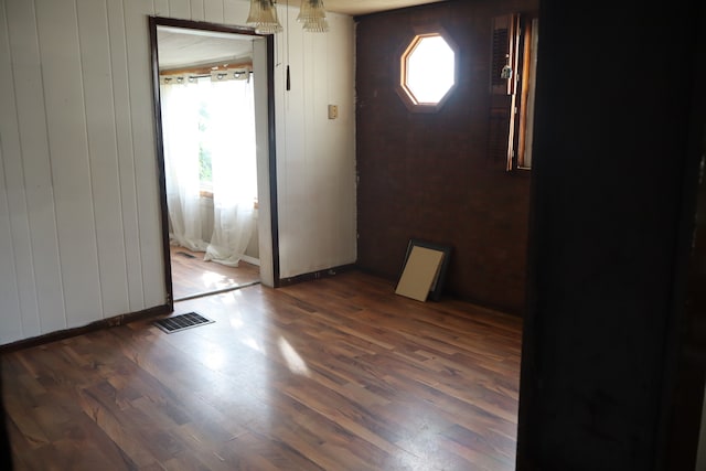 unfurnished room featuring dark wood-type flooring and wooden walls