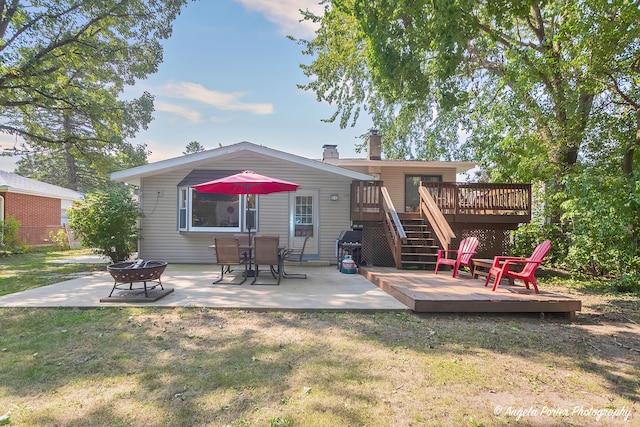 back of property with a chimney, stairway, a patio area, a deck, and a fire pit