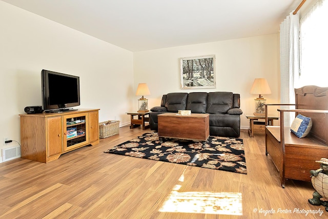 living room featuring baseboards, visible vents, and light wood finished floors