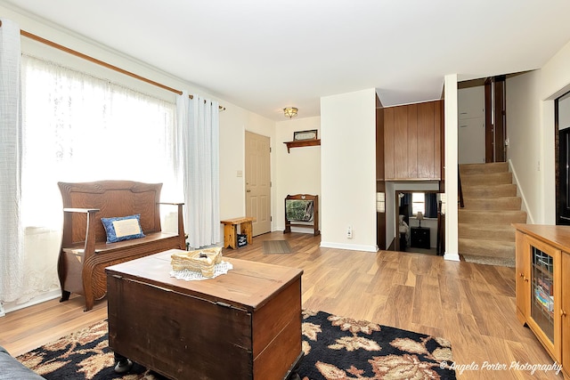 living area with light wood-style flooring, stairs, and baseboards