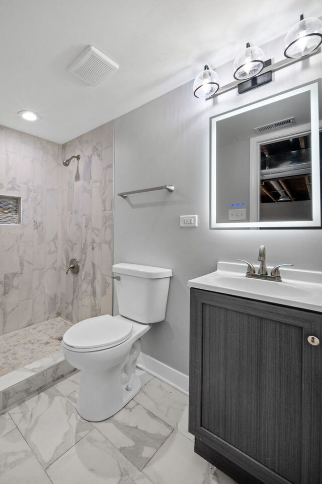 bathroom featuring toilet, vanity, and tiled shower