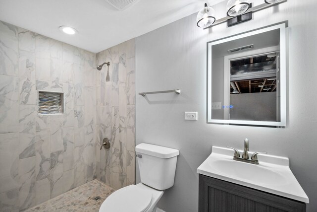 bathroom with a tile shower, vanity, and toilet