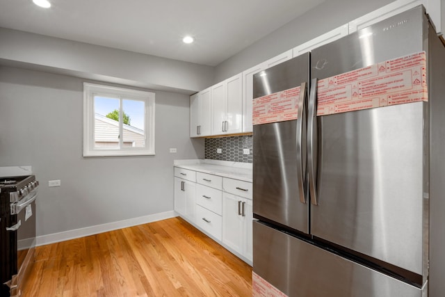 kitchen featuring light wood-type flooring, white cabinetry, stove, and stainless steel refrigerator