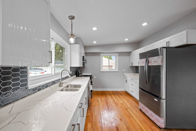 kitchen featuring light stone counters, white cabinets, sink, decorative light fixtures, and stainless steel appliances