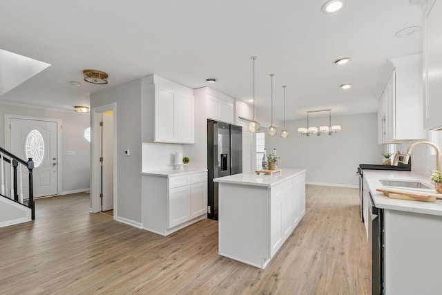 kitchen featuring stainless steel fridge with ice dispenser, decorative light fixtures, a kitchen island, and white cabinetry