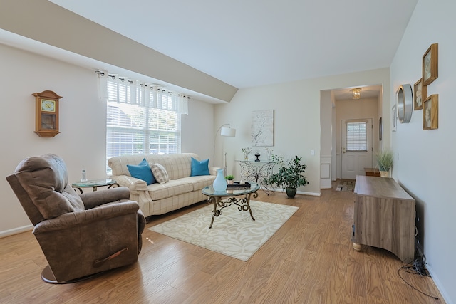 living room featuring lofted ceiling and light hardwood / wood-style floors