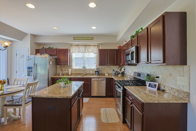 kitchen featuring light hardwood / wood-style floors, backsplash, stainless steel appliances, a center island, and sink