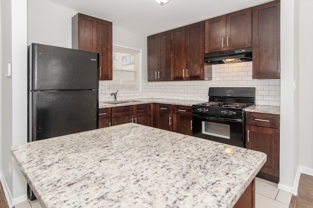 kitchen with light stone counters, tasteful backsplash, black appliances, light hardwood / wood-style flooring, and sink