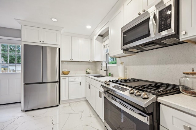 kitchen with white cabinets, plenty of natural light, sink, and stainless steel appliances