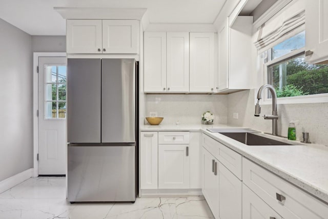 kitchen featuring a wealth of natural light, stainless steel fridge, sink, and white cabinets