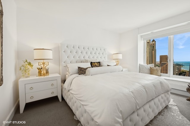 bedroom with dark carpet and a water view