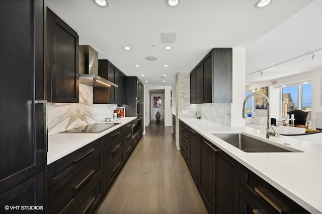 kitchen featuring wall chimney exhaust hood, black electric stovetop, tasteful backsplash, and sink