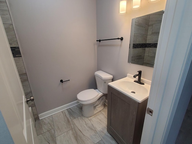 bathroom featuring baseboards, toilet, and vanity