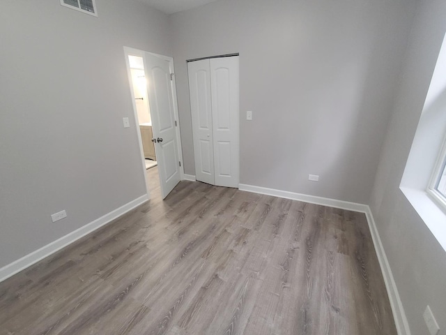 spare room featuring light wood finished floors, visible vents, and baseboards