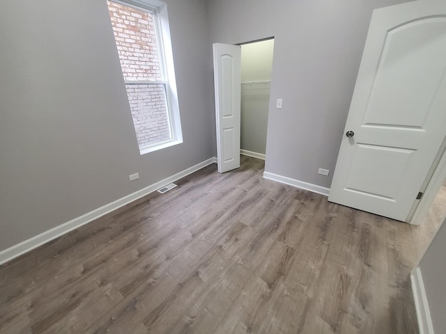 unfurnished bedroom featuring visible vents, baseboards, and wood finished floors