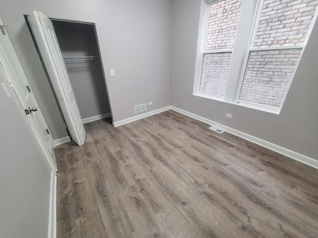 unfurnished bedroom featuring wood finished floors, visible vents, and baseboards