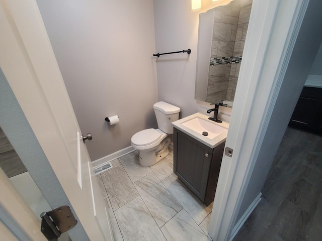 bathroom with vanity, toilet, baseboards, and visible vents