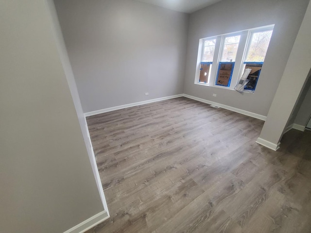 spare room with baseboards and dark wood-style floors