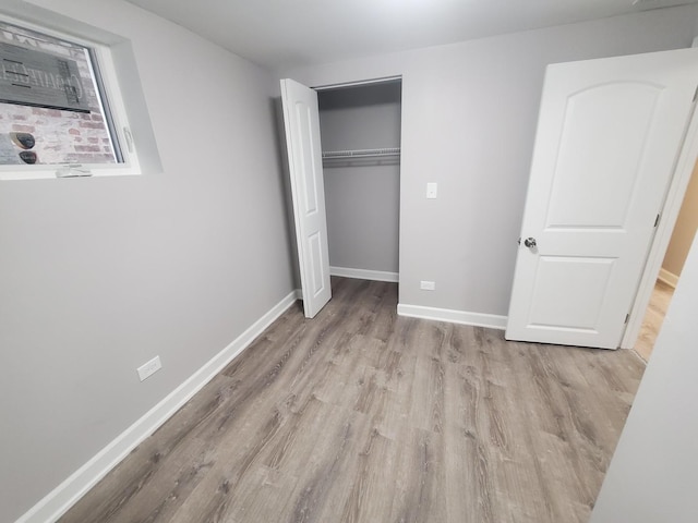 unfurnished bedroom featuring a closet, baseboards, and wood finished floors