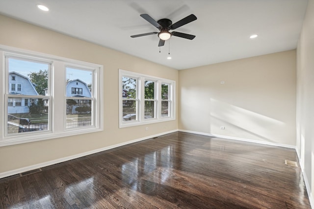 spare room featuring dark wood-type flooring, ceiling fan, and a wealth of natural light