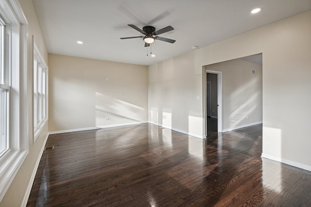 spare room featuring ceiling fan, dark hardwood / wood-style floors, and a healthy amount of sunlight