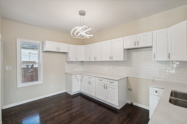 kitchen with light stone counters, hanging light fixtures, dark hardwood / wood-style floors, and white cabinetry