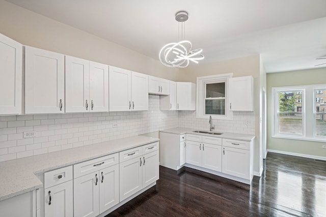 kitchen with white cabinets, hanging light fixtures, sink, backsplash, and dark hardwood / wood-style flooring