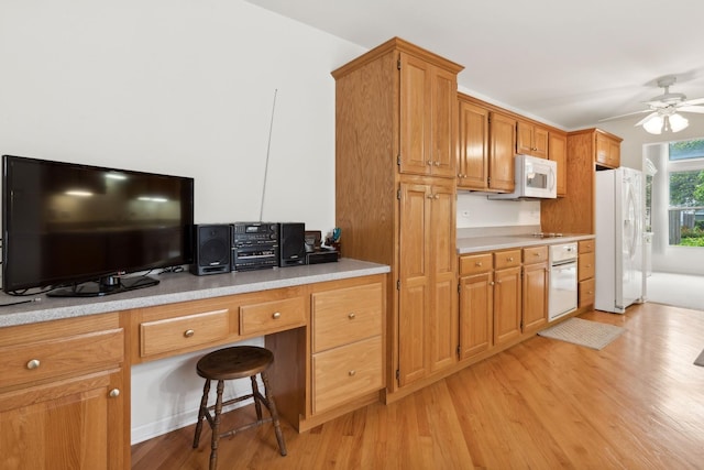 kitchen featuring ceiling fan, light hardwood / wood-style floors, white appliances, a breakfast bar area, and built in desk