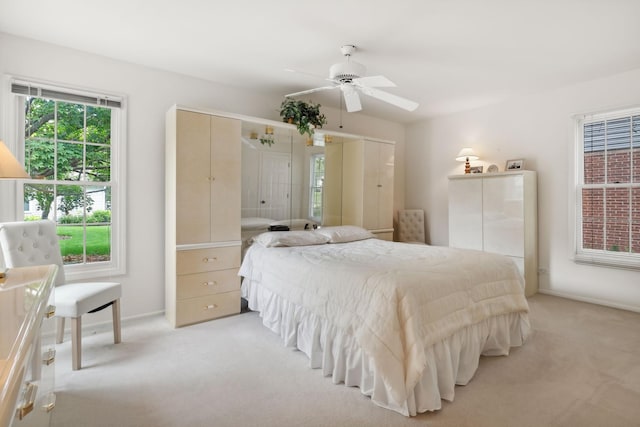 bedroom with multiple closets, ceiling fan, and light carpet